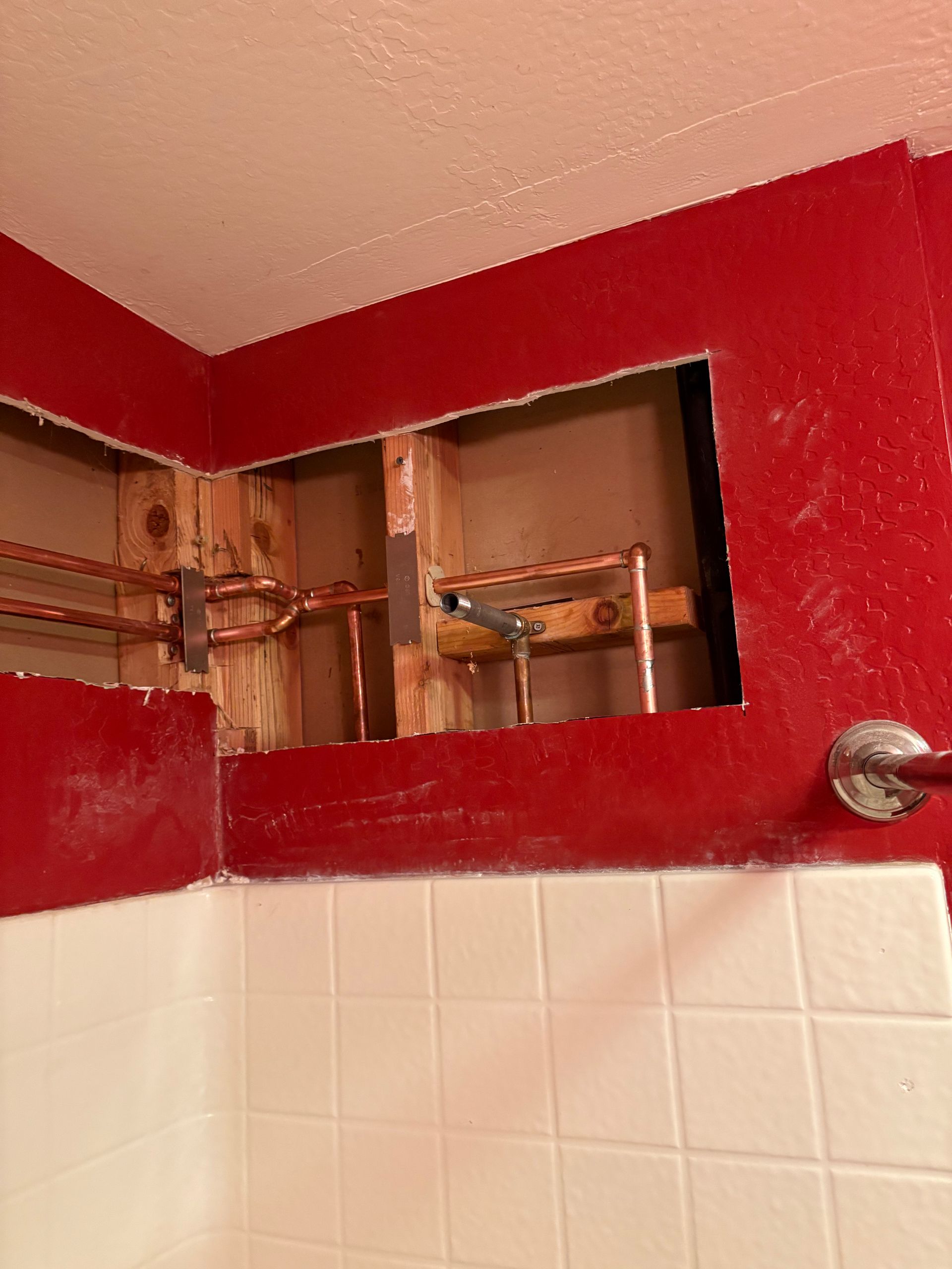 A red wall in a bathroom with a hole in it