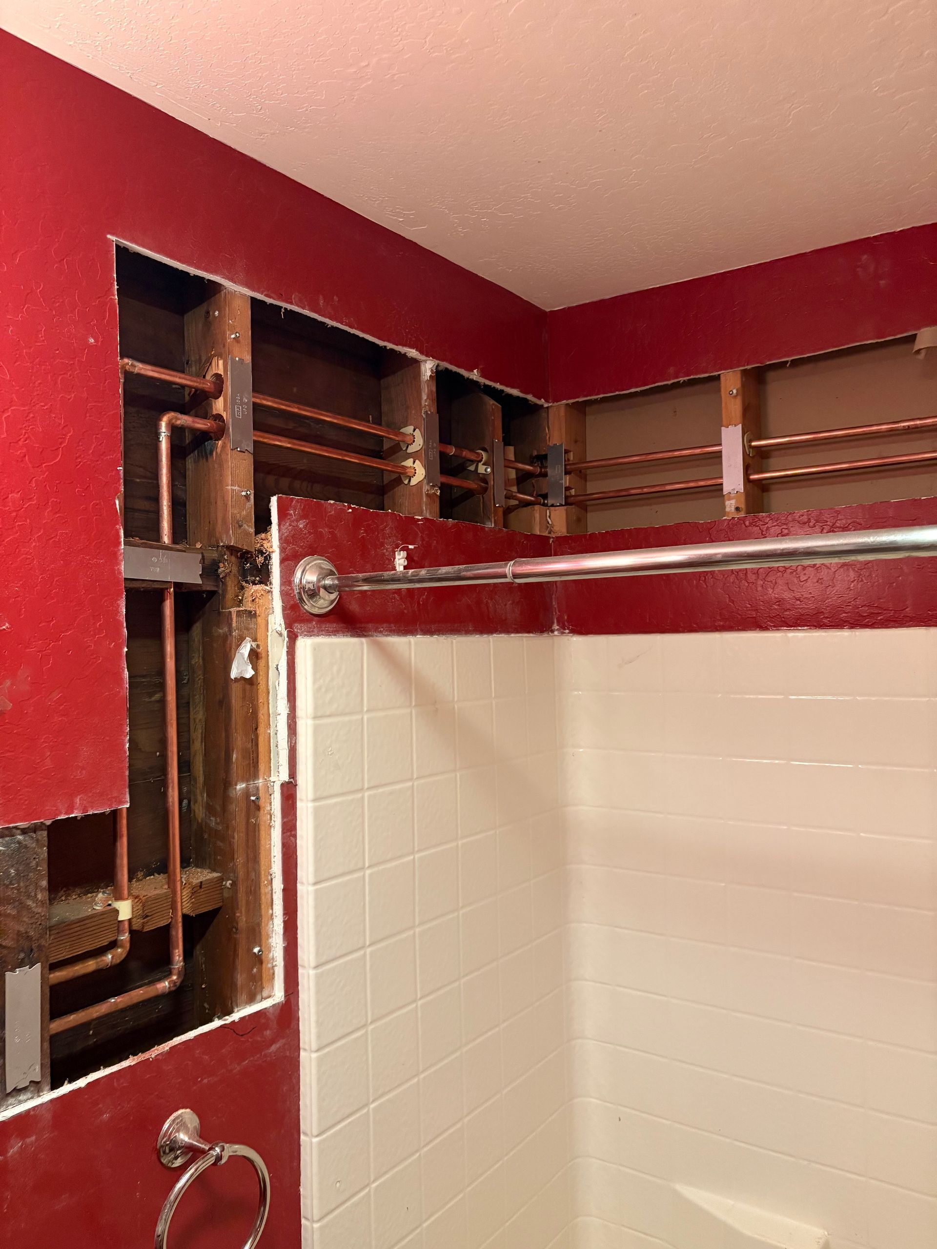 A bathroom with a hole in the wall and a shower head.