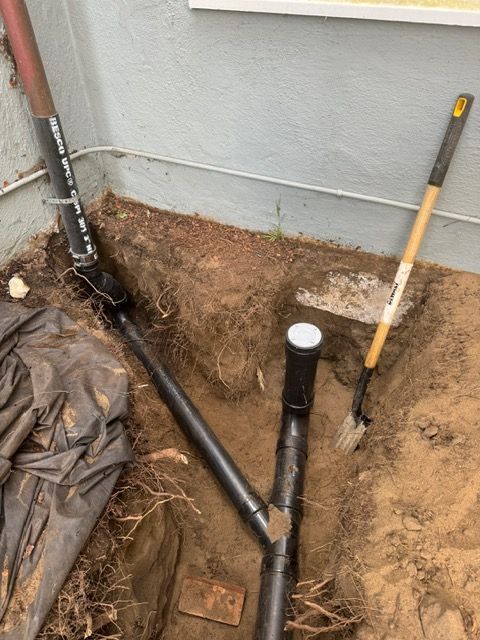 A shovel is laying in the dirt next to a pipe.