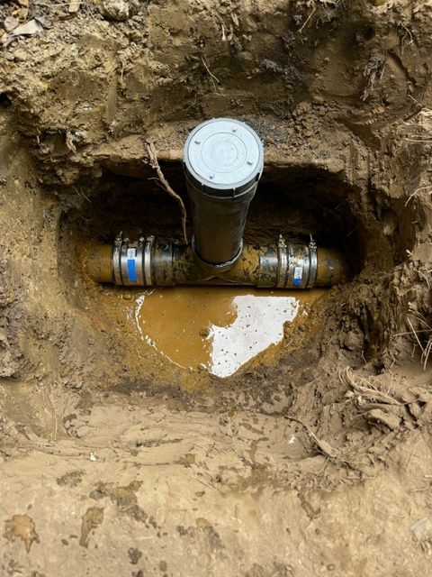 A pipe is sitting in the dirt in a hole.