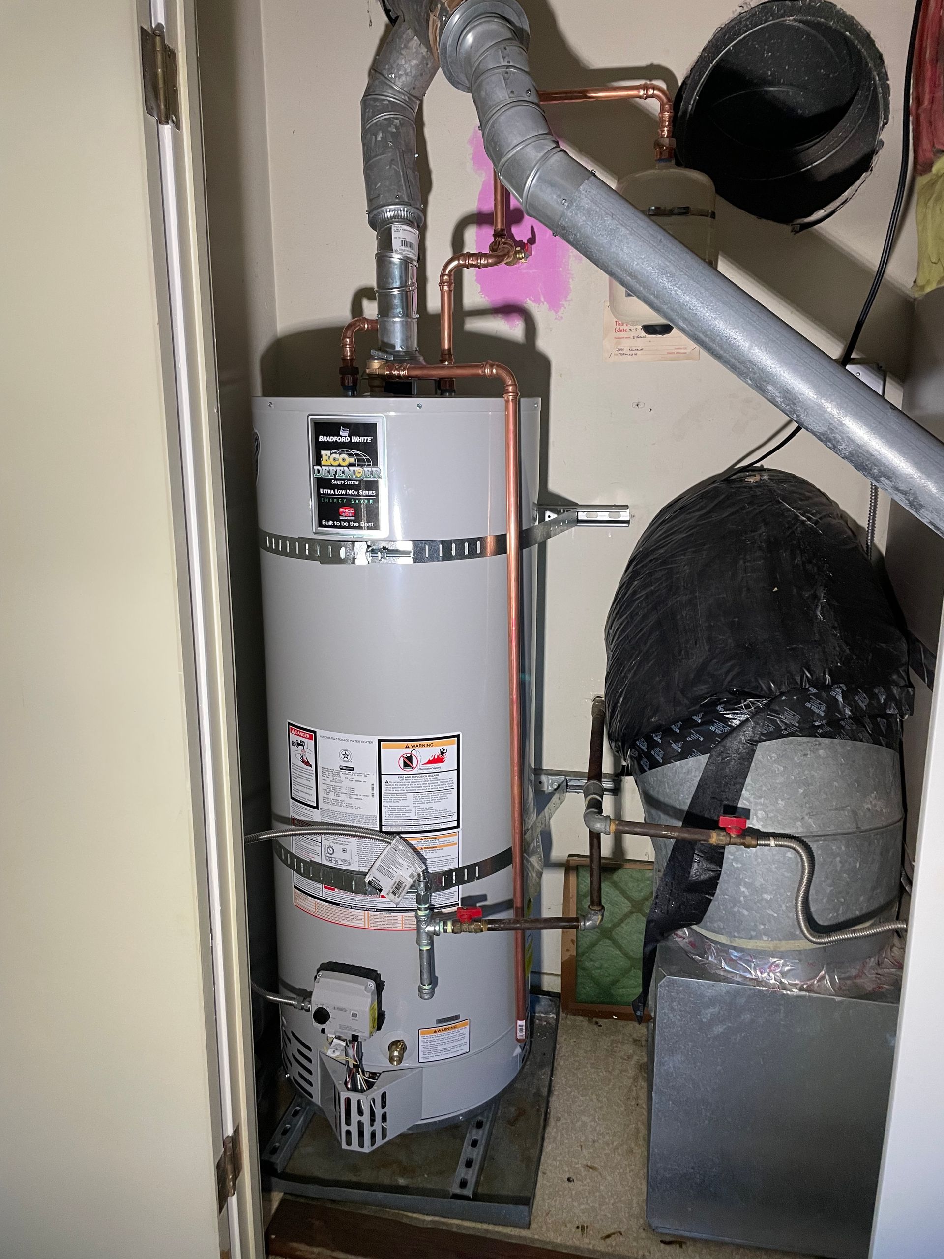 A water heater is sitting in a corner of a room