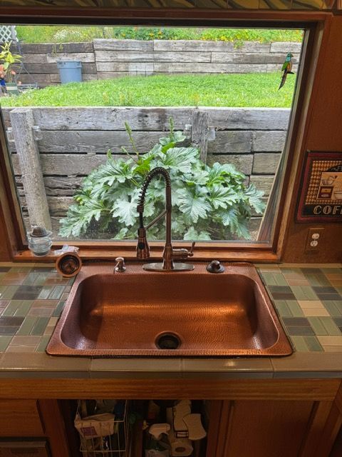 A copper sink with a faucet and a window in a kitchen.