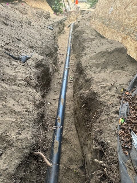 A pipe is being installed in a trench in the dirt.