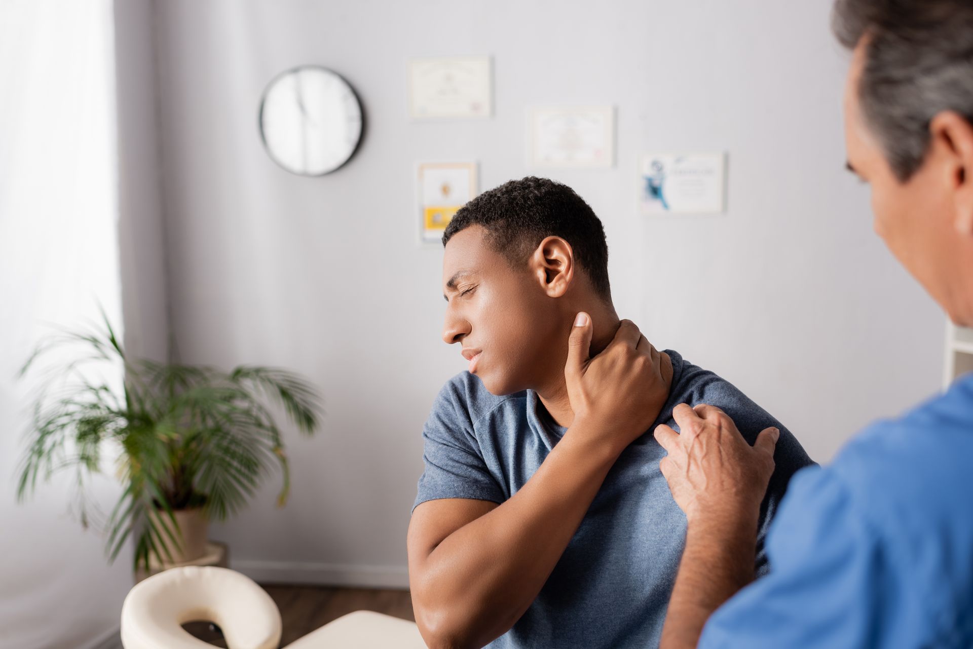A man with neck pain is being checked by a doctor.
