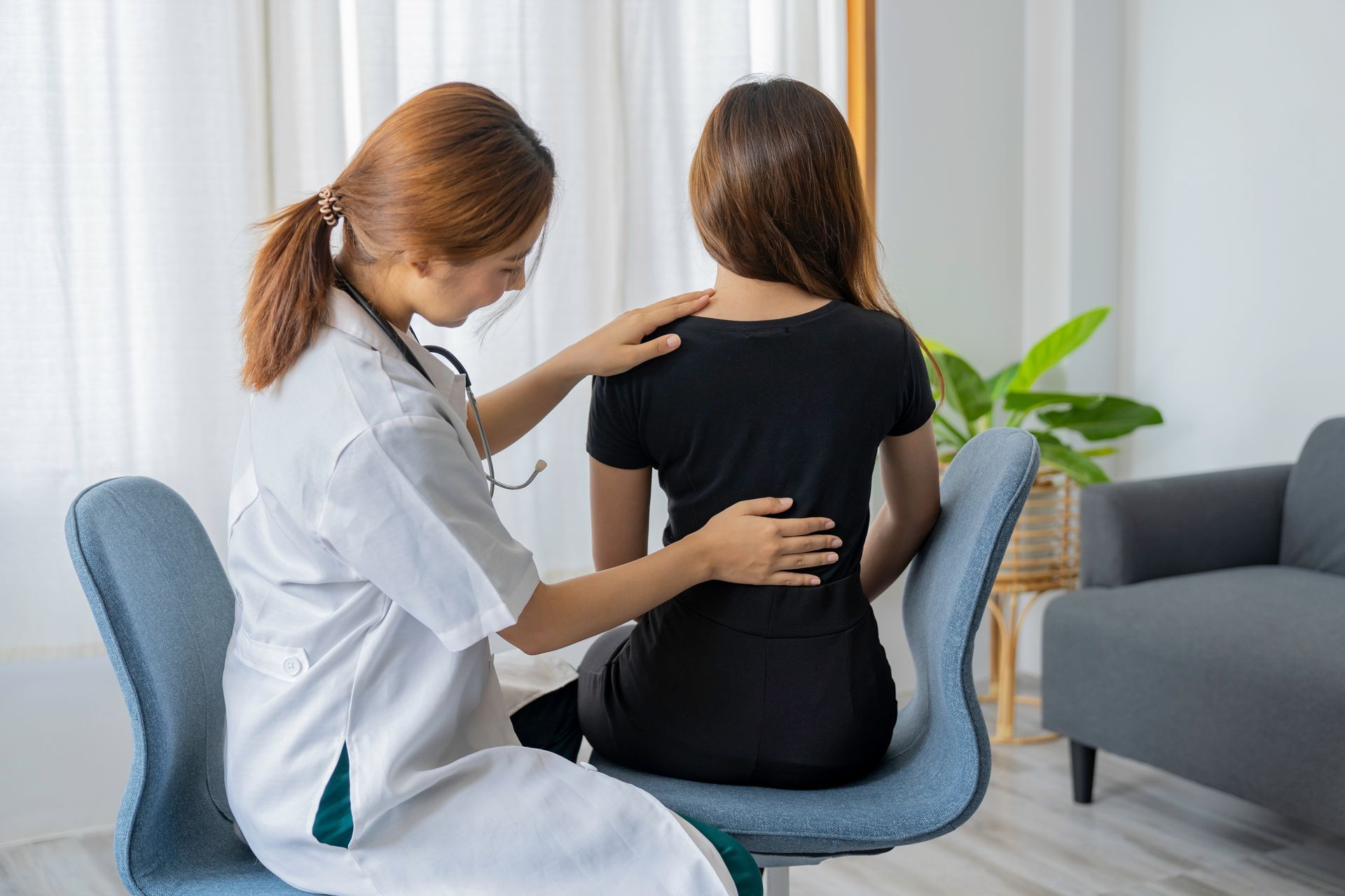 Female doctor doing physiotherapy to treat the back of a female patient.