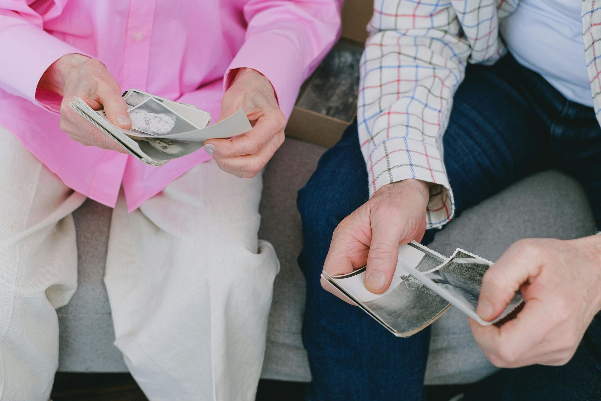 Two people counting money, one in pink shirt, the other in plaid jacket, sitting down.