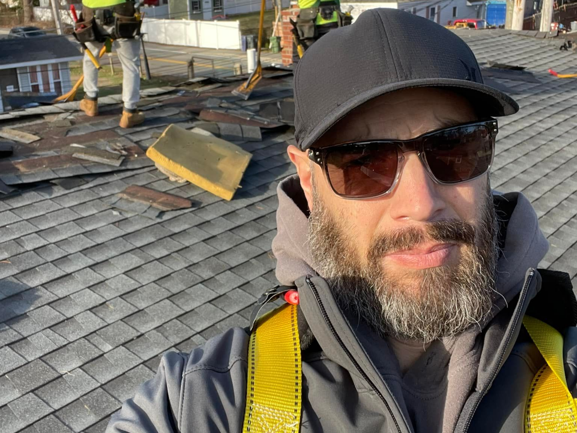 Couple with two dogs outdoors; one held, one on a leash, by a car.