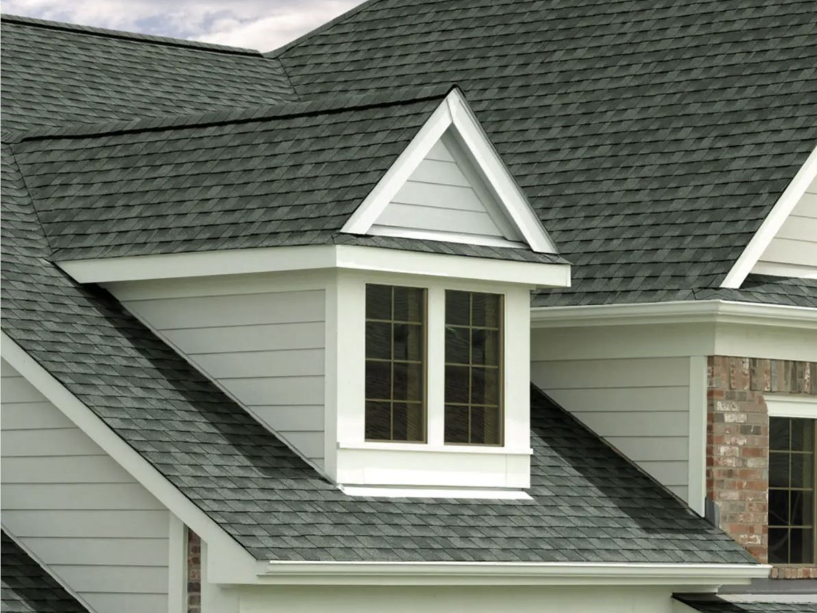 Gray asphalt shingle roof with a white dormer featuring two windows.