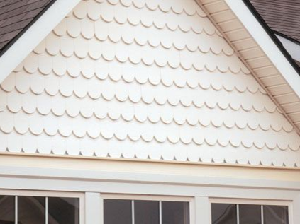 White scalloped siding on a gable above white windows and trim.