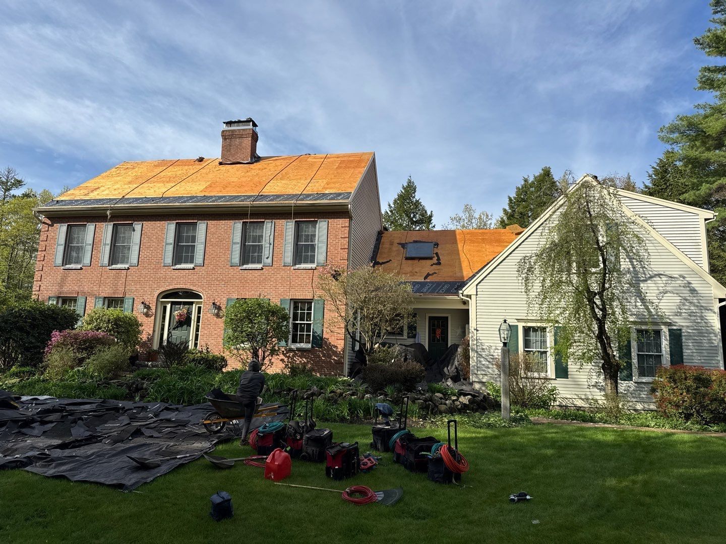 House with roof partially removed during construction; tools and debris on lawn.