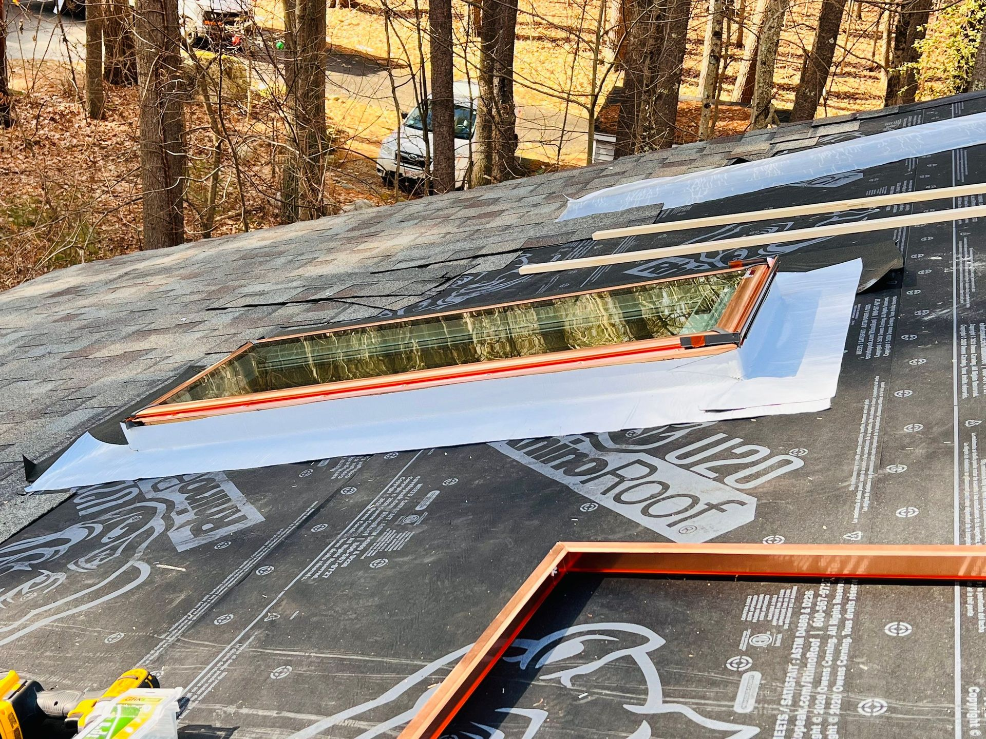 Roof with a skylight being installed; flashing is in place, and the surrounding roof is covered with black underlayment.