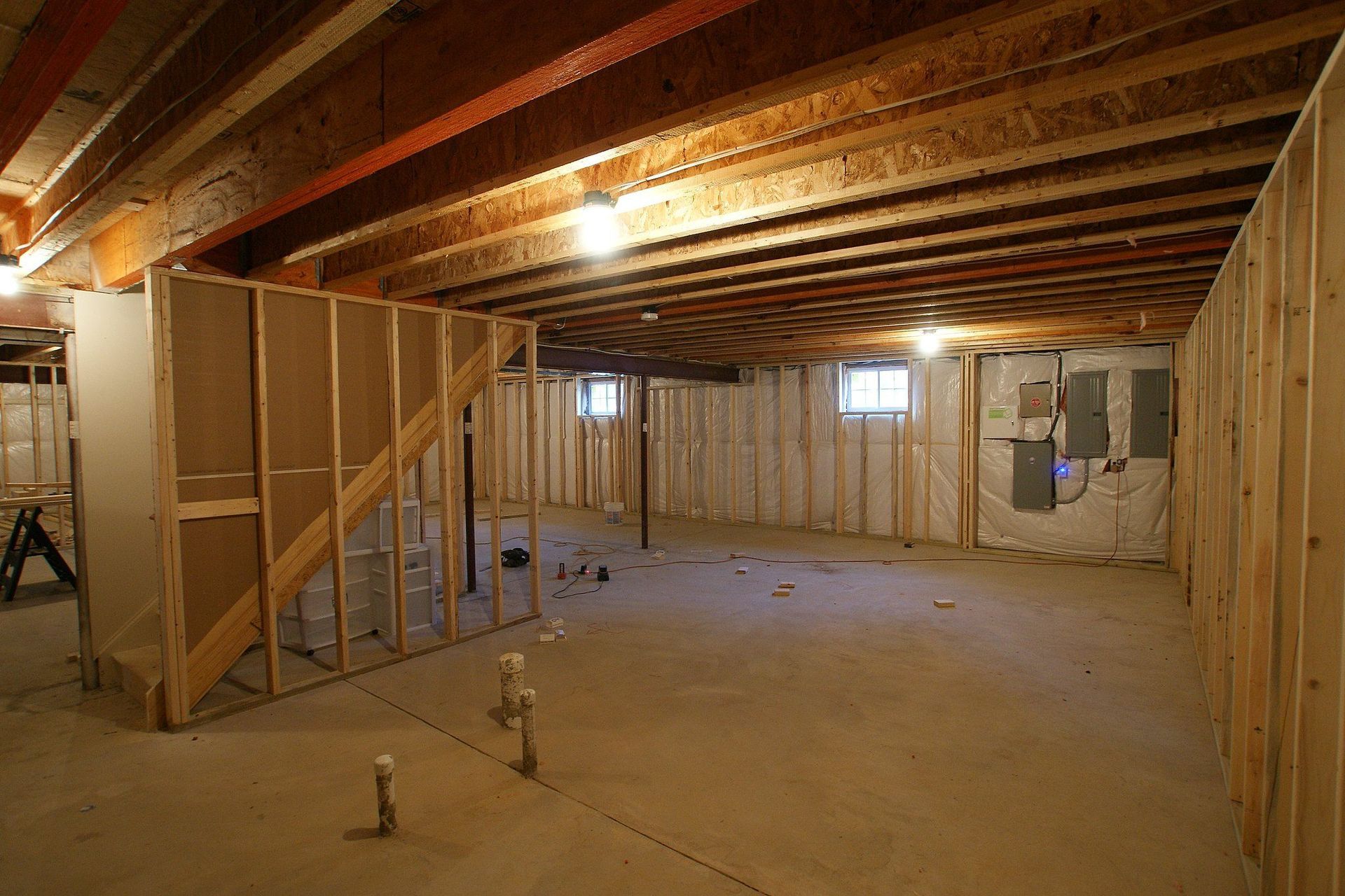 Unfinished basement with wooden framing, exposed ceiling beams, and concrete floor.