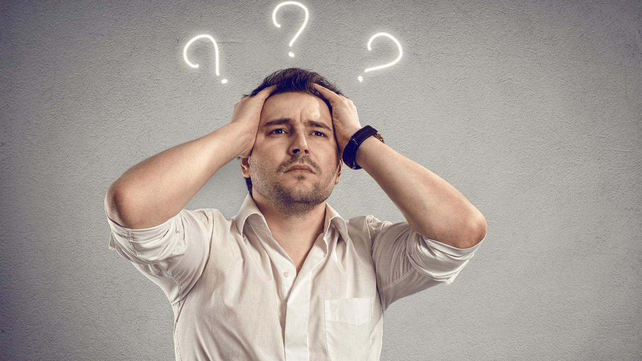 Man with hands on head, looking concerned with three question marks above him.
