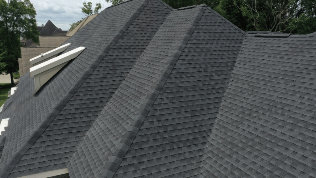 Dark gray shingled roof with multiple angles on a house, with a skylight visible.