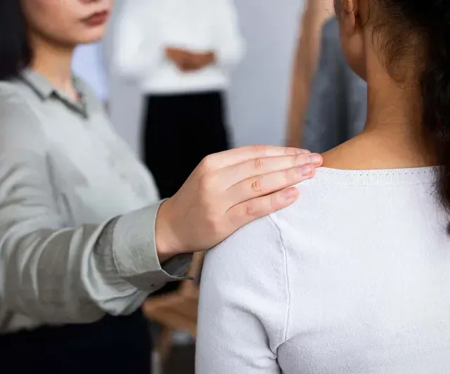 A woman is putting her hand on another woman 's shoulder.