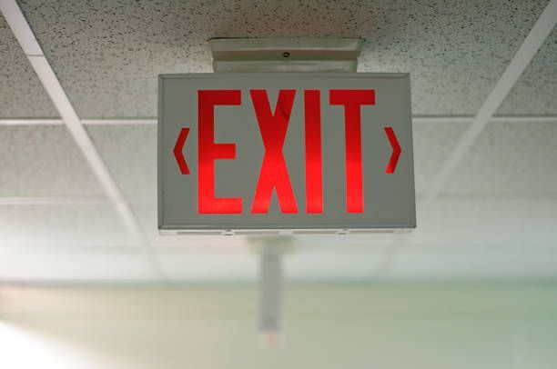 A red exit sign is hanging from the ceiling in a room.