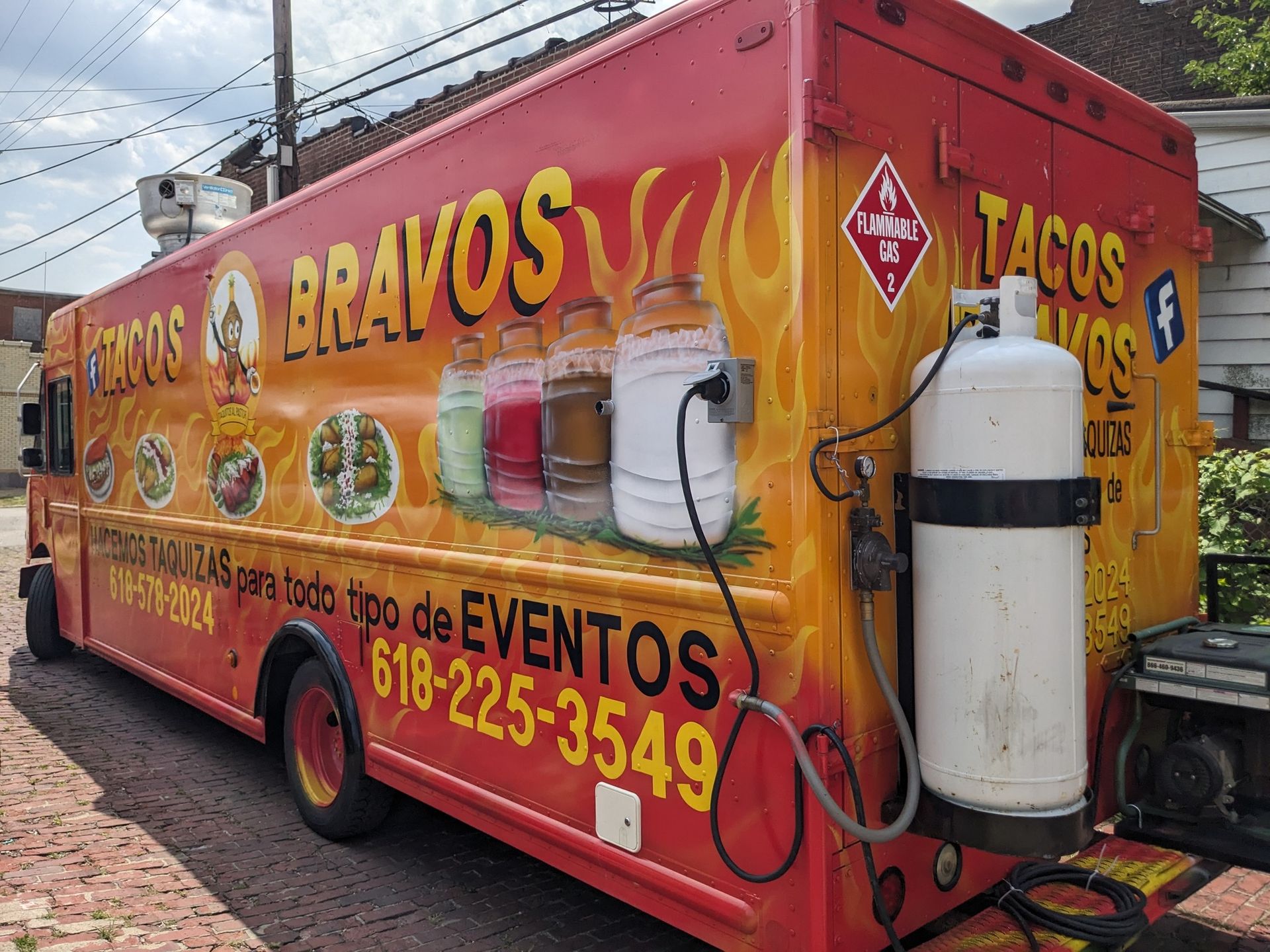 A red and yellow food truck is parked on the side of the road.