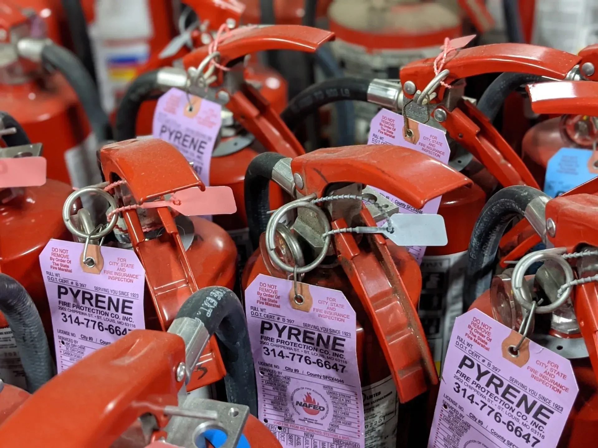 A bunch of fire extinguishers with tags that say pyrene