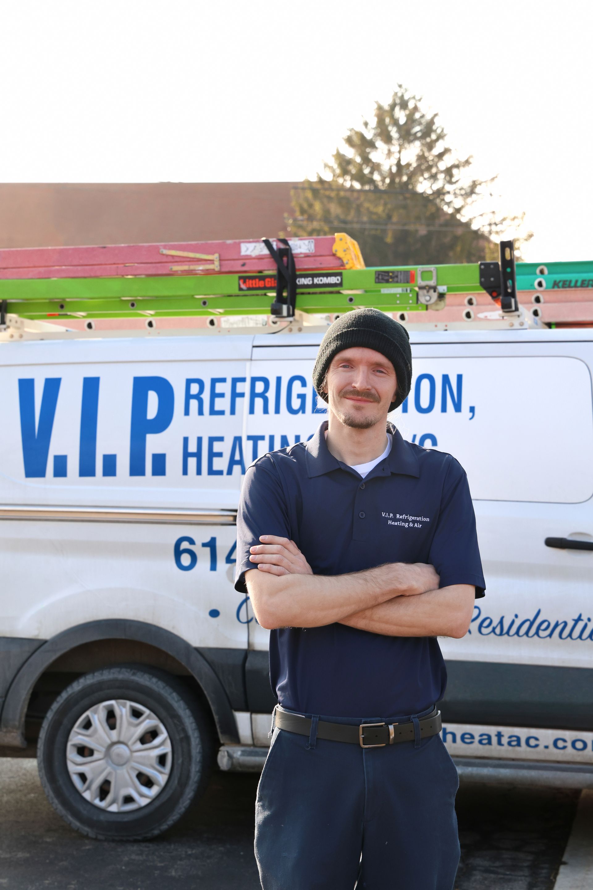 HVAC technician on a rooftop servicing an air conditioning unit. He’s wearing protective gear and using gauges.