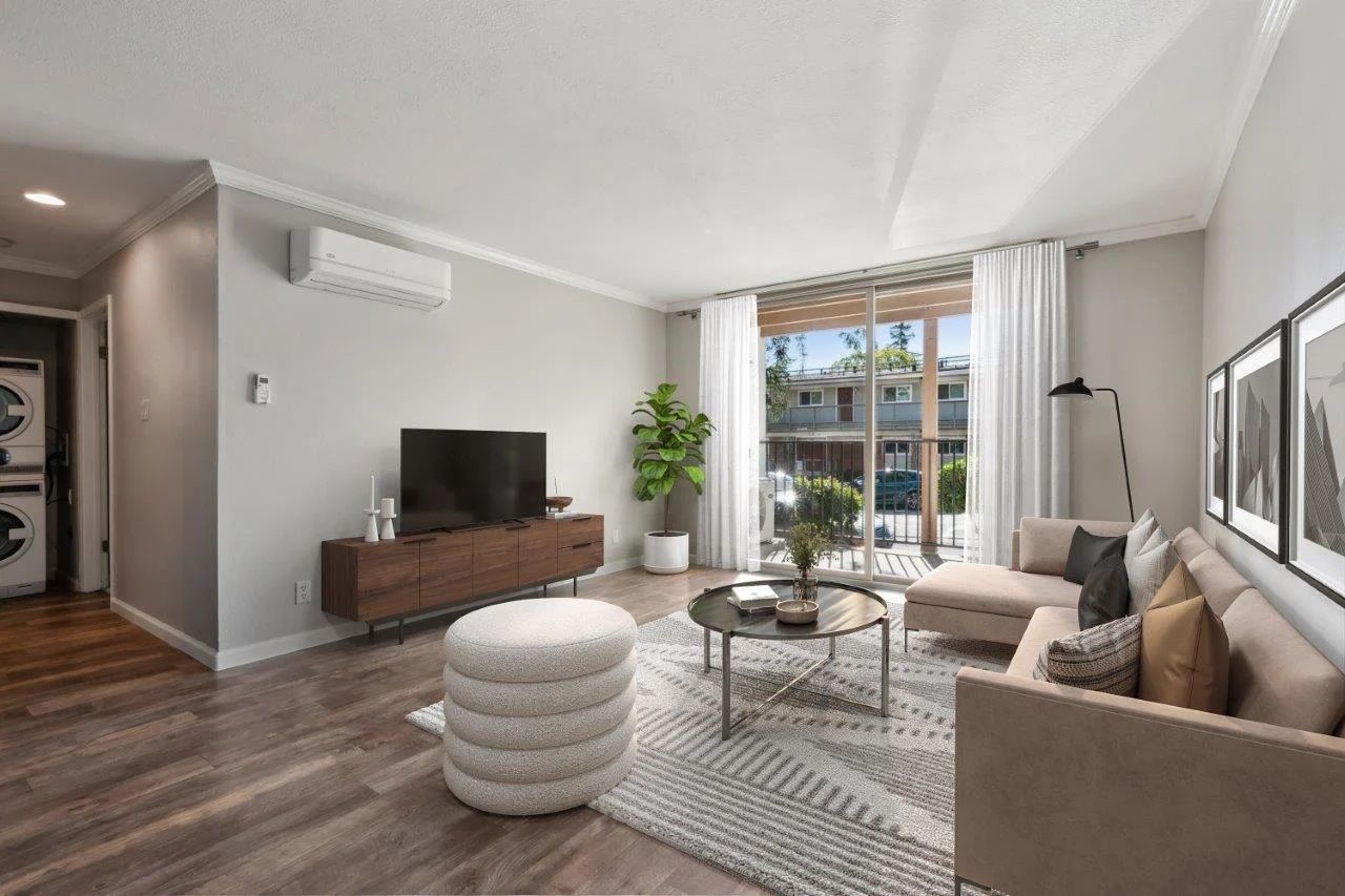 Living room with wood floor, gray walls, a tv on a brown console, and beige furniture.