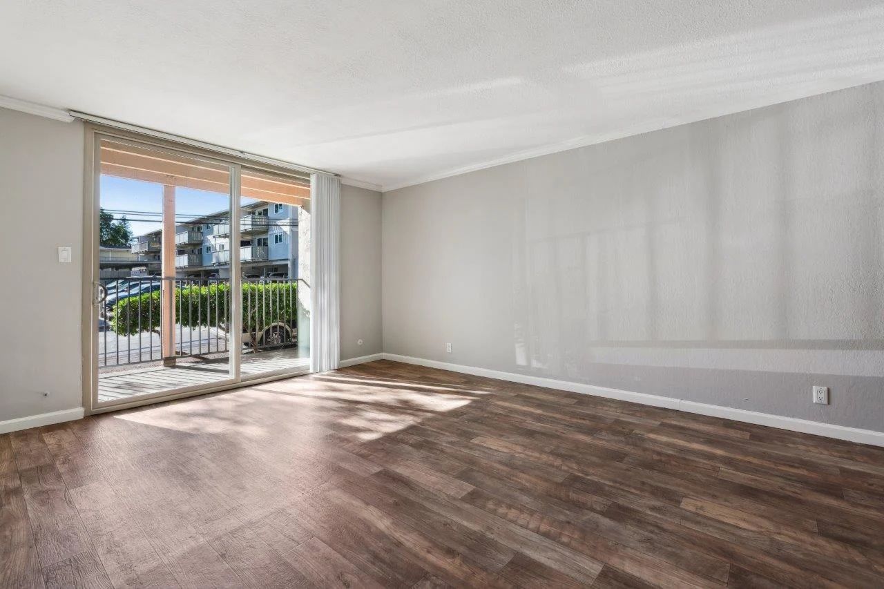 Empty room with wood floors, sliding glass door, and gray walls.