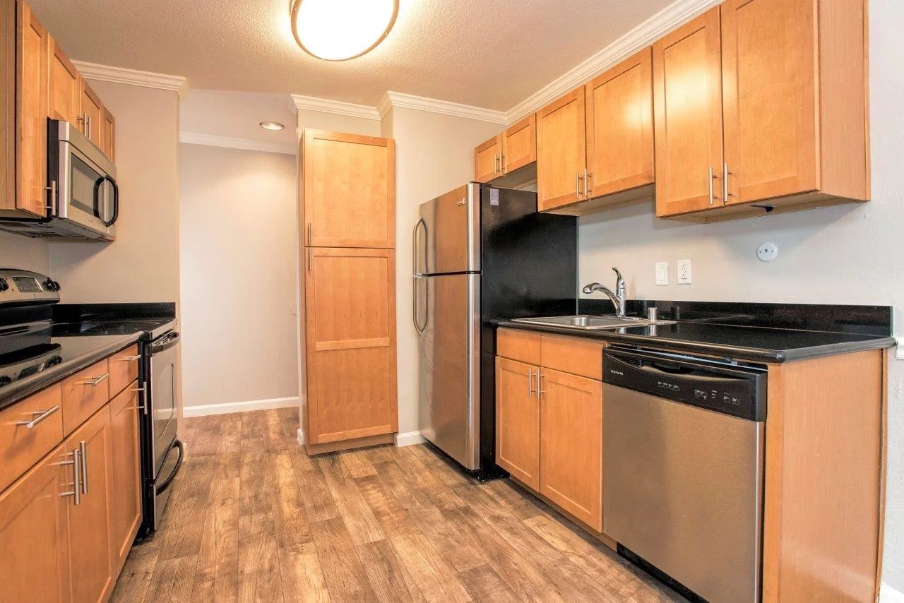 Kitchen with light brown cabinets, stainless steel appliances, and wood-look flooring.