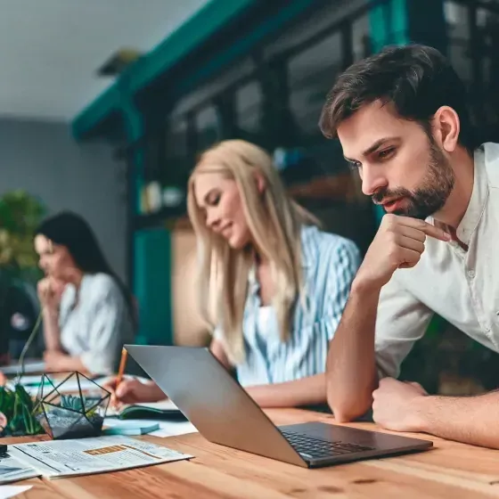A group of people are sitting at a table using laptops.