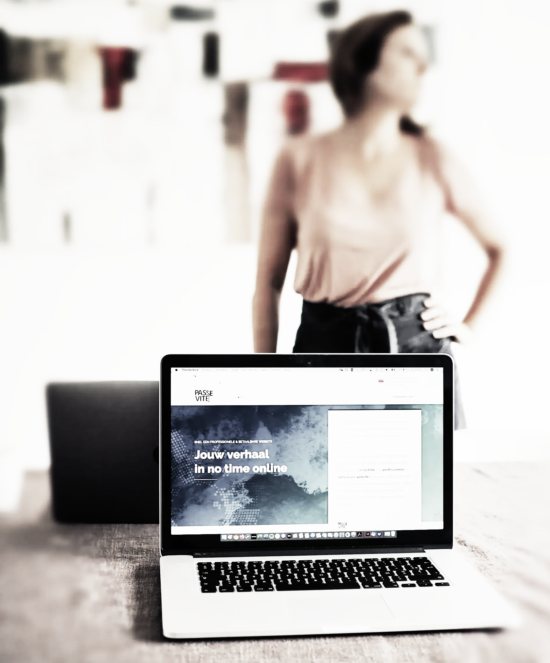 Een vrouw staat voor een laptop met een website erop