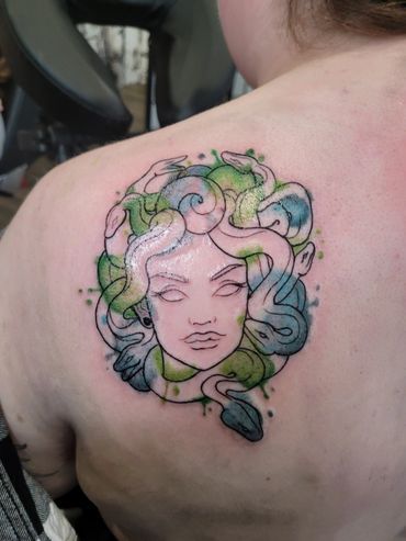 A woman has a medusa tattoo on her back.