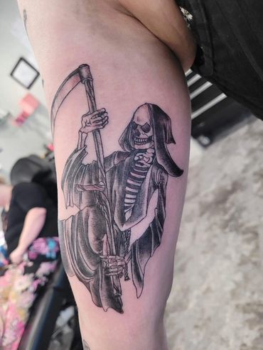 A person has a grim reaper tattoo on their arm.