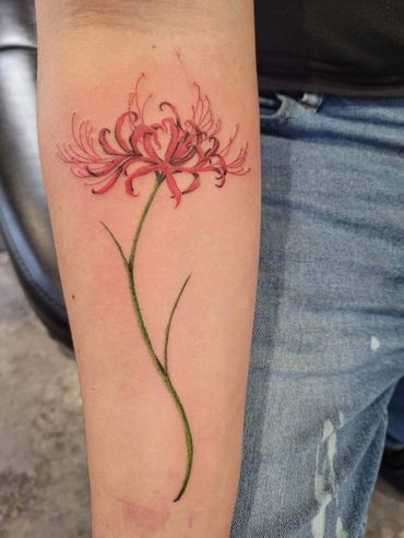 A person has a tattoo of a red flower on their forearm.