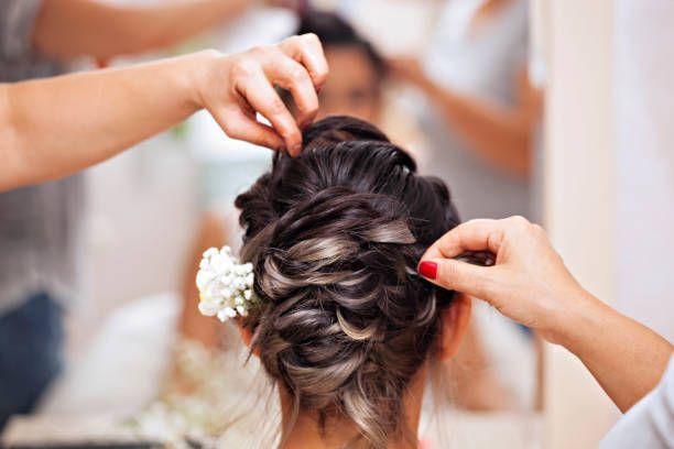 A woman is getting her hair done by a hairdresser in front of a mirror.