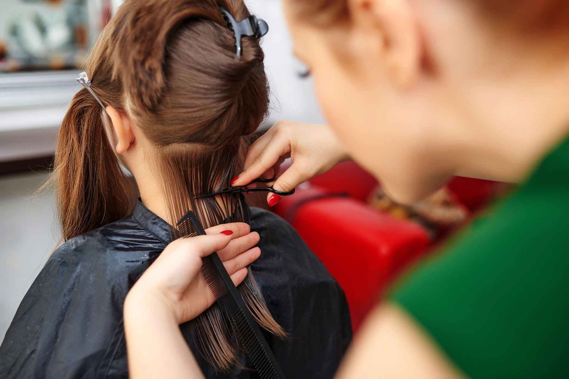 A woman is getting her hair cut by a hairdresser.