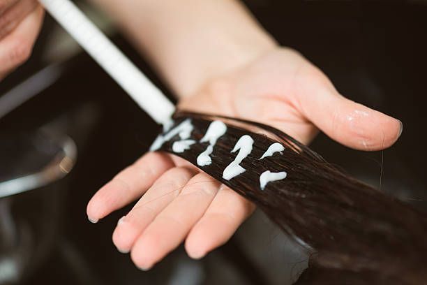A close up of a person holding a piece of hair with cream on it