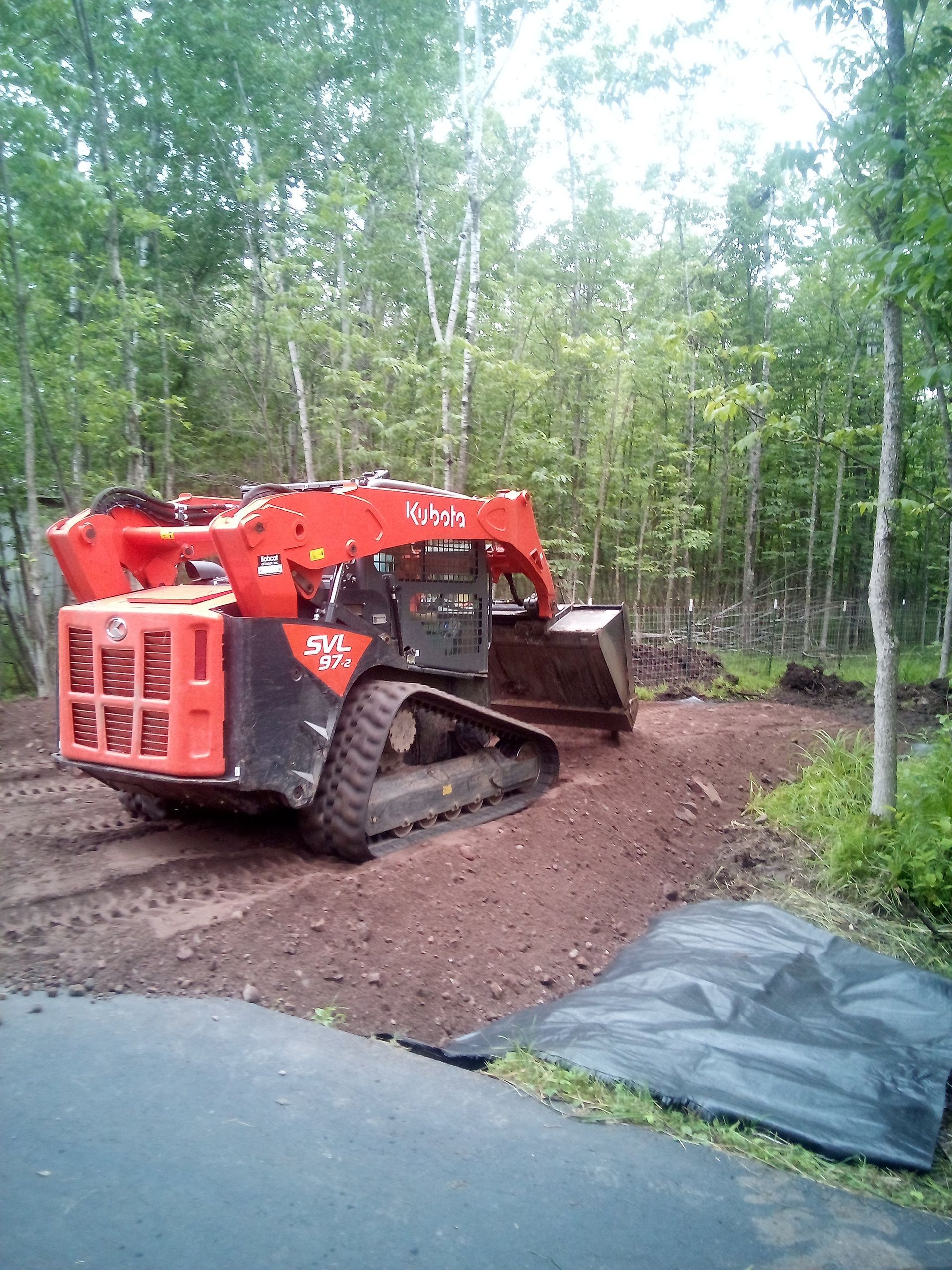 A bulldozer is sitting on a dirt road in the middle of a forest.