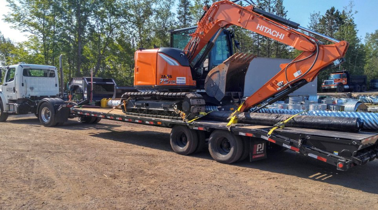 An excavator is sitting on top of a flatbed trailer.