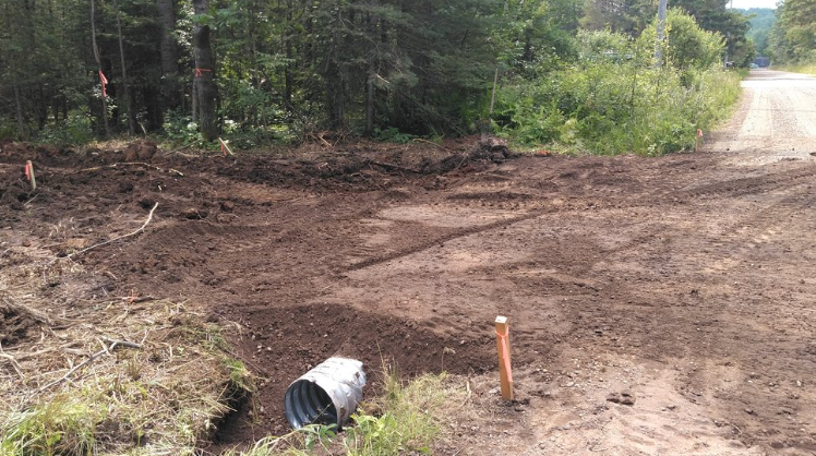 A bucket is sitting in the middle of a dirt road.