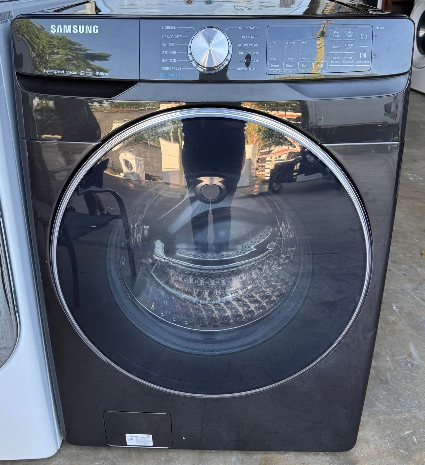 Black Samsung front-load washing machine. It has a large, round glass door and control panel at the top.