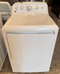 A white GE clothes dryer with a control panel on top, the door is closed.