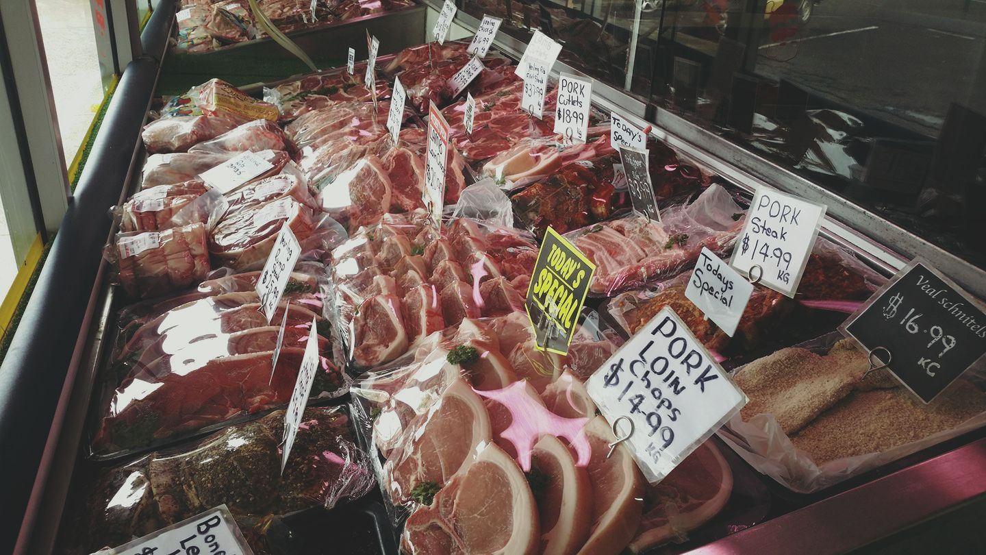 Saleswoman Offering Fresh Meat at Display in Supermarket — Byron Bay Pork & Meats Butchery in Mullumbimby, NSW