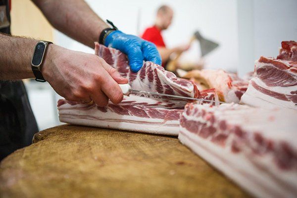 Butcher Carefully Chopping a Large Portion of  Meat — Byron Bay Pork & Meats Butchery in Byron Bay, NSW