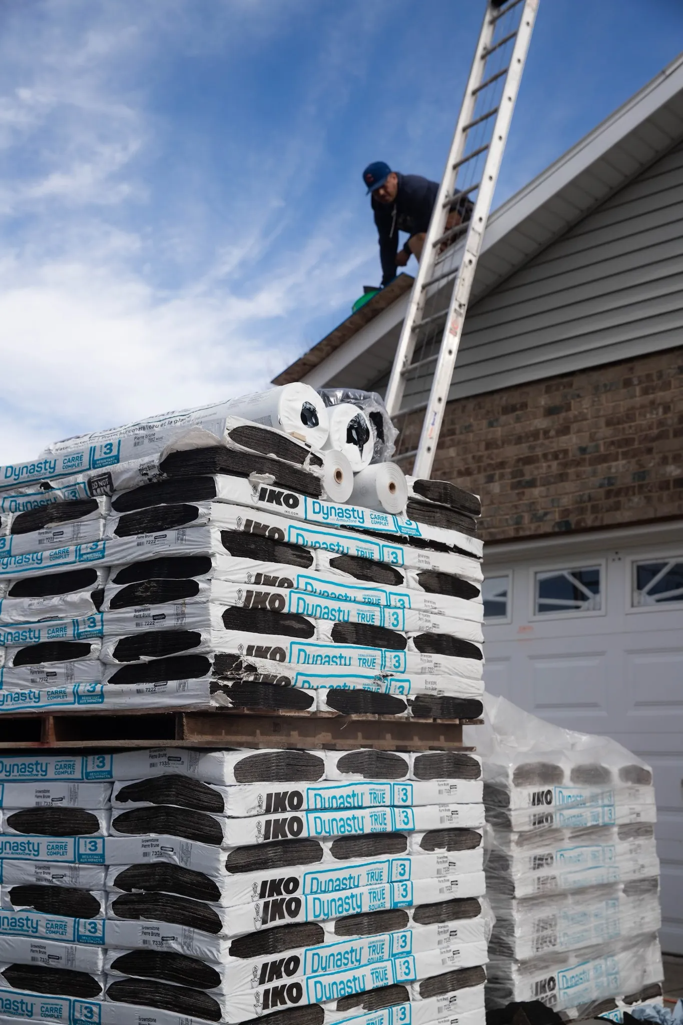 A man is standing on a ladder on top of a stack of bags.
