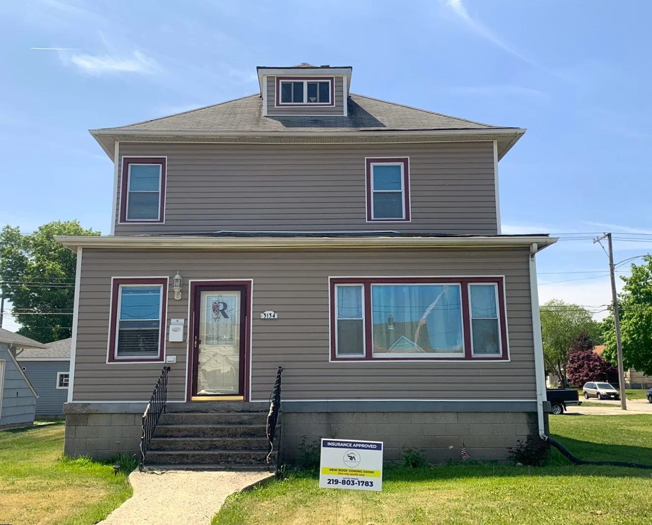 A large house with a lot of windows and a sign in front of it.