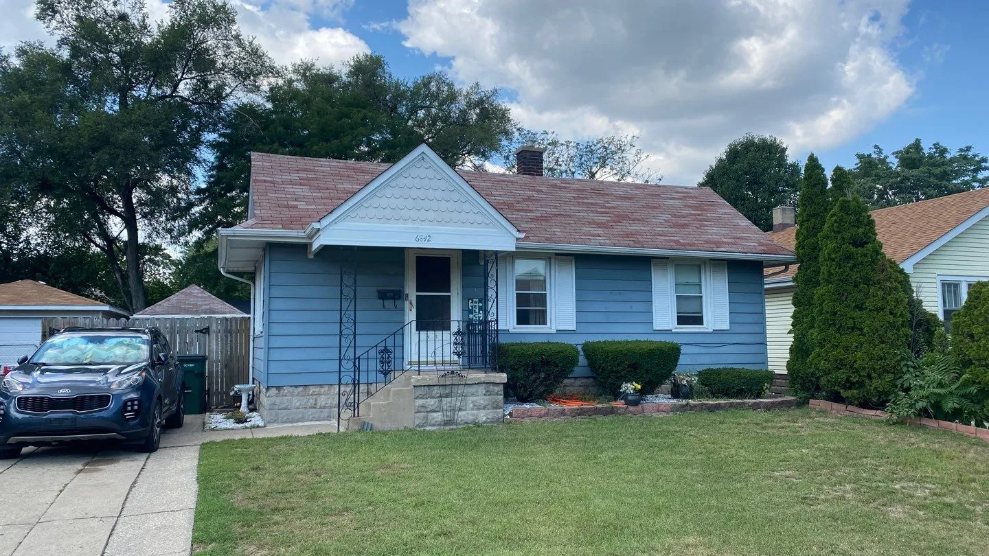 A blue house with a car parked in front of it.