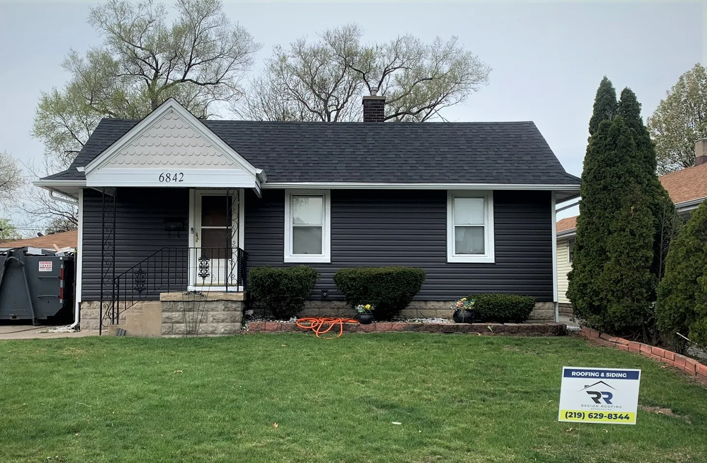 A small black house with a sign in front of it.