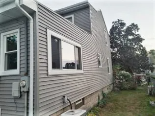 The side of a house with a lot of windows and an air conditioner.