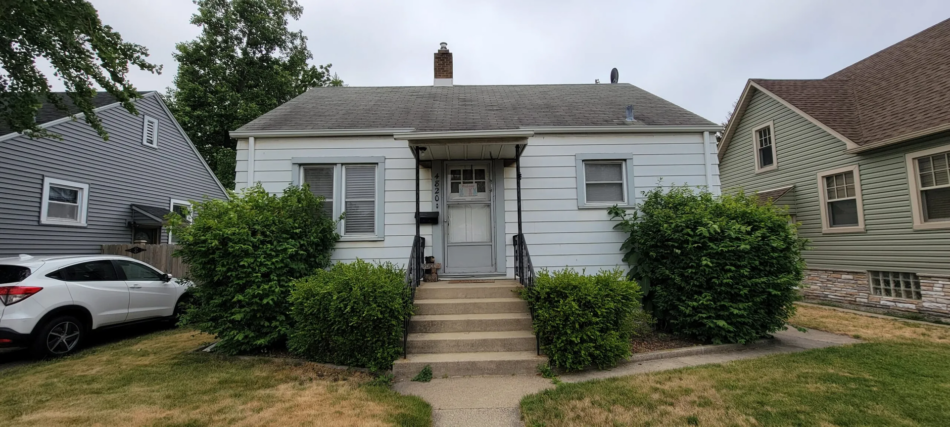 A small white house with a car parked in front of it.