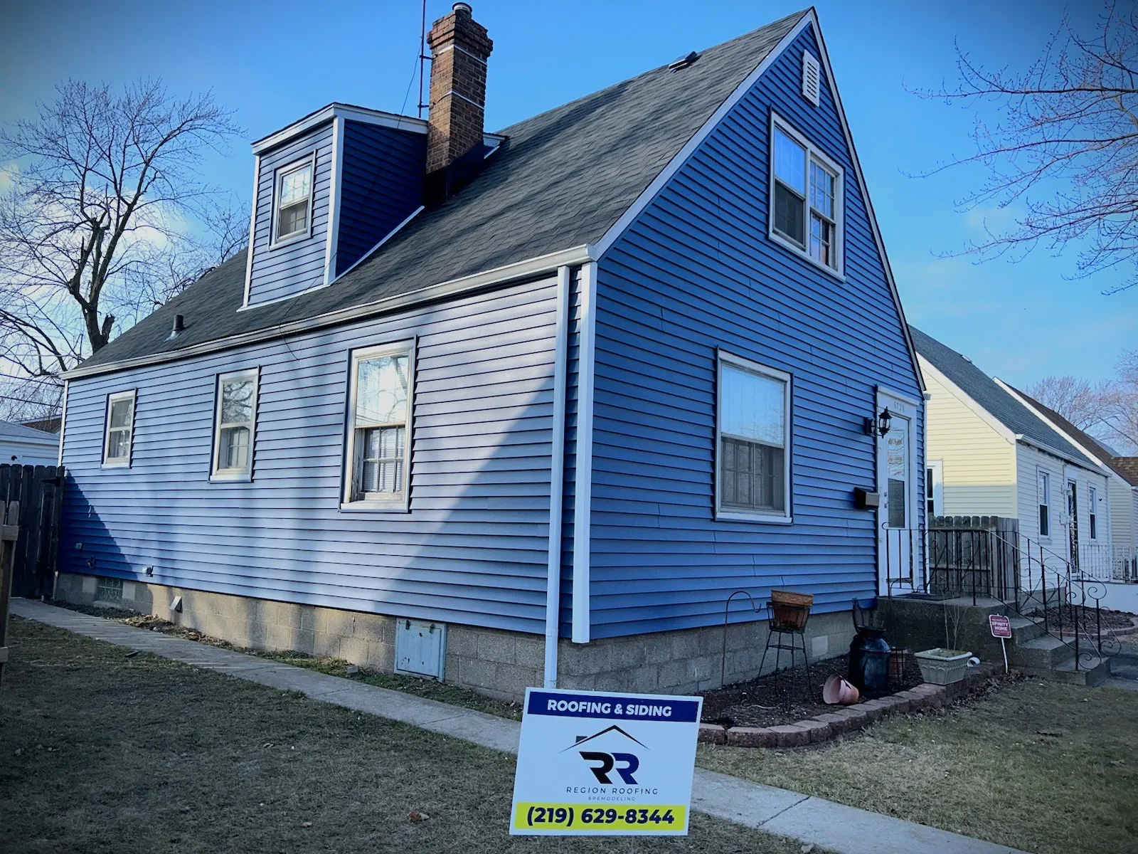 A blue house with a for sale sign in front of it.