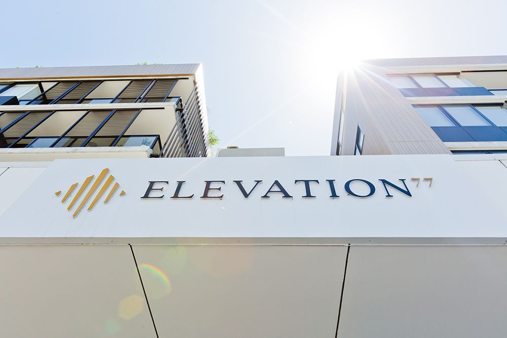 Elevation 77 building sign with modern architecture against a sunny sky.