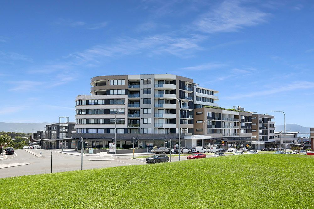 Modern multi-story apartment building with glass balconies on a sunny day.